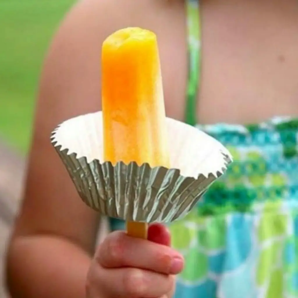 Child holding popsicle with muffin paper 