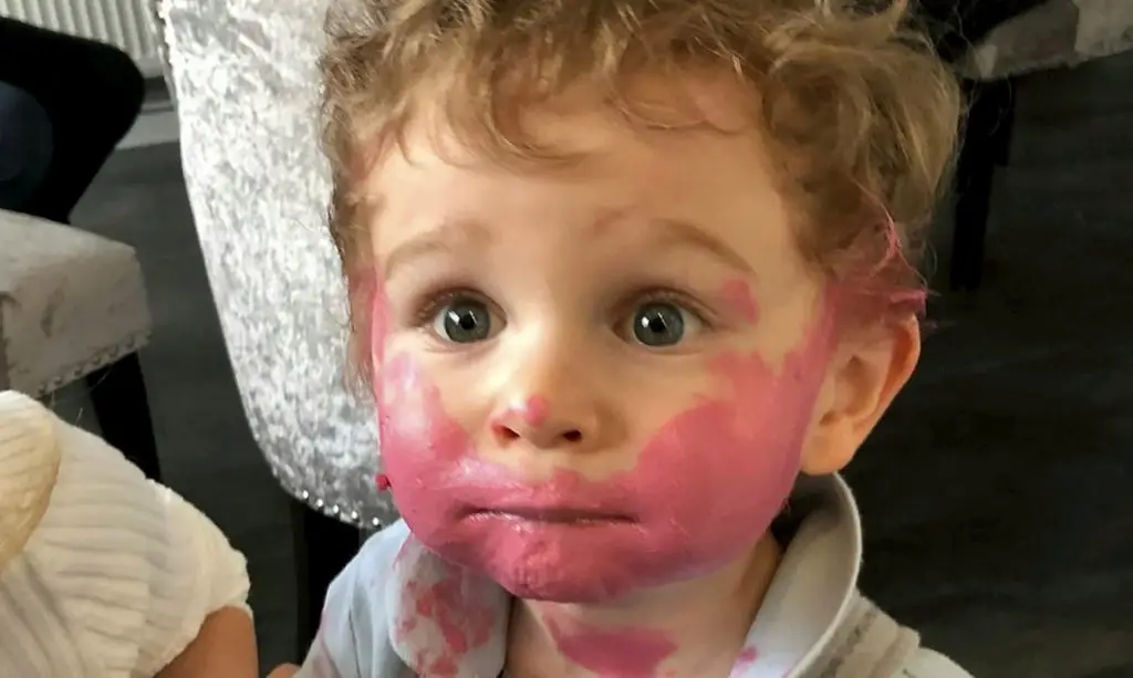 Boy with his mom's lipstick all over his face