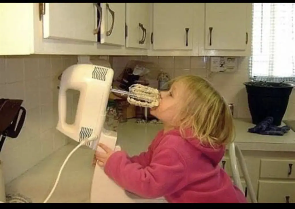 Girl liking the batter of an electric mixer