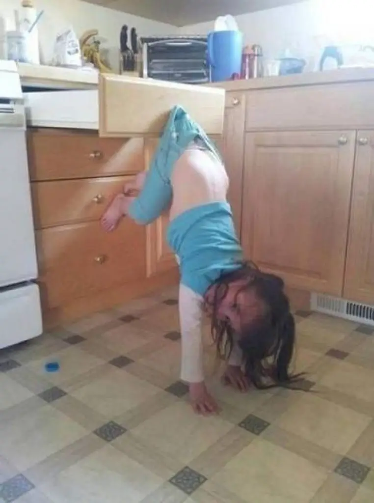 Little girl upside down stuck on a drawer